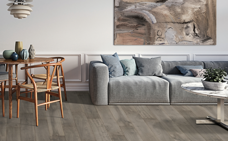 wood look laminate flooring in living room with grey couches