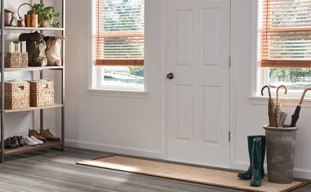 custom wood blinds in entry way by front door with vinyl wood-look flooring